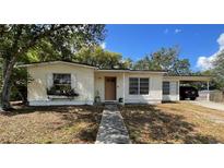 Charming single-story home featuring a cozy front porch and an adjacent car port, surrounded by mature trees at 2332 Hadley St, Deltona, FL 32738