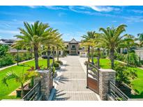 Grand estate featuring a brick driveway lined with mature palm trees and lush landscaping under a bright blue sky at 2636 S Peninsula Dr, Daytona Beach, FL 32118
