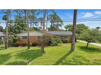 Charming brick ranch home with mature landscaping and a well-manicured lawn at 44 Fairway Cir, New Smyrna Beach, FL 32168