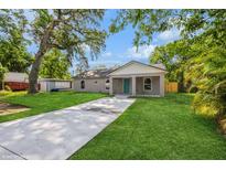 Charming single-story home with a well-manicured lawn, long driveway and a blue front door at 495 6Th St, Holly Hill, FL 32117