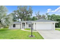Charming single-story home boasts a manicured lawn, mature trees, and an attached two-car garage at 941 Pizarro Dr, Daytona Beach, FL 32119