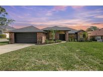 Charming brick home with a well-manicured lawn and professional landscaping, with an attached two-car garage at 104 Balmoral Ct, Debary, FL 32713