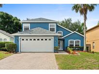 Charming two-story blue home with a manicured lawn, a brick driveway, and a two-car garage at 109 Fern Springs St, Debary, FL 32713