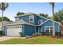 Charming two-story blue home with a manicured lawn, a brick driveway, and a two-car garage at 109 Fern Springs St, Debary, FL 32713
