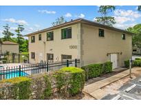 Exterior of a two-story condo building featuring a pool, black fence, and well-maintained landscaping at 1601 Big Tree Rd # 1302, South Daytona, FL 32119