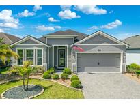 Beautiful single-Gathering home featuring a paved driveway, two-car garage, manicured lawn, and traditional landscaping at 165 Azure Mist Way, Daytona Beach, FL 32124
