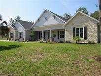 Beautiful single-story home featuring manicured landscaping, stone accents, and a welcoming covered porch at 1870 Pepper Tree Ln, Deland, FL 32720