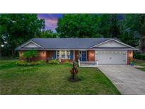 Charming brick home featuring a manicured lawn, mature trees, and a two-car garage at 20 Monroe Ave, Debary, FL 32713