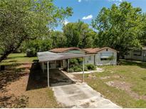 Quaint single-story home featuring a covered carport and surrounded by lush greenery at 29505 North, Paisley, FL 32767