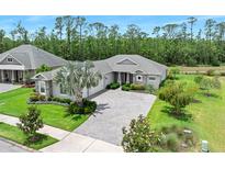 Beautifully landscaped front yard with paver driveway and mature palm tree at 3322 Modena Way, New Smyrna Beach, FL 32168