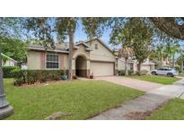 Charming single Gathering house featuring tan siding, arched doorway, and manicured lawn at 680 Preakness Cir, Deland, FL 32724