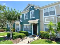 Charming blue townhome with well-manicured landscaping, walkway, and dark front door, with a tree on the left at 783 Shropshire Loop, Sanford, FL 32771