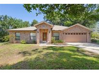 Charming single-story brick home with a well-manicured lawn and attached two car garage at 1120 W Glen Falls Rd, Deland, FL 32720