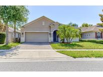 Charming single-story home featuring a well-manicured lawn, palm tree, and a two-car garage at 12079 Alder Branch Loop, Orlando, FL 32824