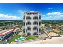 Stunning aerial view of oceanfront condo tower with pool and beach access under sunny sky at 1420 N Atlantic Ave # 202, Daytona Beach, FL 32118