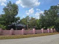 Home featuring a pink block fence, mature landscaping, and a view of the house at 16880 Se 63Rd Ln, Ocklawaha, FL 32179