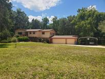 Charming two-story home with a large front yard, two car garage, and an attached car port at 1725 Turtle Hill Rd, Enterprise, FL 32725