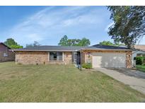 Charming brick home with well-manicured lawn and attached two-car garage under a sunny blue sky at 1904 Viking Ave, Deltona, FL 32725