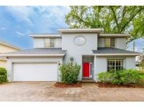 Two-story home with gray siding, a red front door, paver driveway, and mature landscaping at 2418 Formosa Ave, Orlando, FL 32804