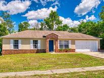 Charming single-story home with a brick facade, an attached two-car garage and well-manicured front yard at 2978 Greynolds St, Deltona, FL 32738
