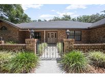 Charming brick home entrance with wrought iron gate and manicured landscaping at 3357 Black Willow Trl, Deland, FL 32724