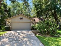 Charming home features a stone facade and well-manicured landscaping around a two car garage at 37 Meadowwood Trl, Deland, FL 32724