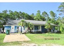 Charming single-story home featuring a covered porch, mature trees, and lush lawn at 3788 Fir Ct, Ormond Beach, FL 32174