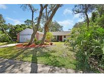 Landscaped front yard with a charming single-story home featuring a red front door and attached garage at 5967 Plantera Ct, Port Orange, FL 32127