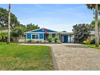 Charming blue home featuring a paved driveway, lush green lawn, and tropical landscaping in the front yard at 809 E 14Th Ave, New Smyrna Beach, FL 32169