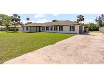 Charming single-story home with a well-manicured lawn and a long concrete driveway at 825 Wells Dr, South Daytona, FL 32119