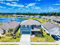 Beautiful two-story blue home with a well-manicured lawn, complemented by a serene lake view and fountain at 918 Noble Run, New Smyrna Beach, FL 32168