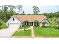 Charming brick home featuring manicured lawn, symmetrical landscaping, and attached two car garage at 160 Point O Woods Dr, Daytona Beach, FL 32114
