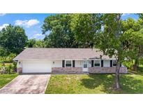 Charming one-story home featuring a brick facade, attached garage, and well-manicured lawn on a sunny day at 2106 Umbrella Tree Dr, Edgewater, FL 32141