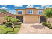 Two-story townhome featuring an attached garage, screened porch, brick driveway, and well-maintained landscaping at 302 Tammie Sue Ln, Deland, FL 32724