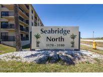 Sign for Seabridge North Condominiums, with tropical palm trees, surrounded by white rocks and grass at 3170 Ocean Shore Blvd # 5010, Ormond Beach, FL 32176
