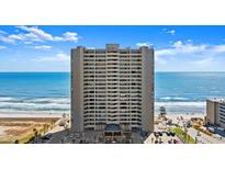Exterior shot of condo building near the beach with the ocean view in the background and a parking lot at the bottom at 3425 S Atlantic Ave # 1602, Daytona Beach, FL 32118