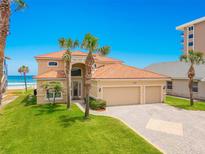 Stunning beachfront home with tile roof, three-car garage, and lush landscaping with swaying palm trees at 4427 S Atlantic Ave, Port Orange, FL 32127