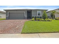 Charming one-story home with a well-manicured lawn, brick driveway, and beautiful landscaping at 460 Sarah Nicole Way, New Smyrna Beach, FL 32168