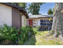 Charming home with a red front door, brick accents and lush landscaping welcomes you to this cozy abode at 5 Greenfern Cir, Ormond Beach, FL 32174