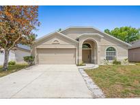 Charming one-story home featuring a beige exterior, attached two-car garage and manicured lawn at 700 Spring Cavern Ave, Orange City, FL 32763