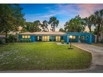 Charming blue single-story home with a manicured lawn and covered carport at sunset at 10 Madera Rd, Debary, FL 32713