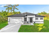 Charming single-story home featuring a two-car garage, landscaped yard, and modern architectural details in neutral tones at 1163 W Hancock Dr, Deltona, FL 32725