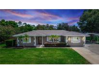 Charming single-story home featuring a well-manicured lawn, mature trees, and a covered parking area at 136 W Gardenia Dr, Orange City, FL 32763