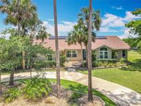 Inviting home featuring lush landscaping, a circular driveway, and solar panels on the roof at 1520 Stone Trl, Enterprise, FL 32725