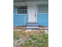 Charming blue house featuring a secure white door and freshly painted concrete steps at 20422 Canvas Back Rd, Altoona, FL 32702