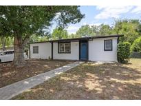 Charming single-story home featuring a blue front door, white siding, and mature landscaping at 2434 Barbarossa Ave, Deltona, FL 32738