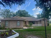 Charming brick home featuring a well-maintained front yard with lush landscaping and a welcoming entrance at 2885 Newmark Dr, Deltona, FL 32738