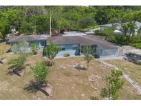 Charming, one-story blue home featuring mature landscaping and a unique decorative carport screen at 45 S University Cir, Deland, FL 32724