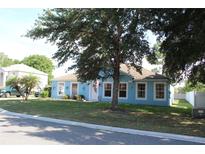 Charming blue single-story home with white trim, a well-manicured lawn, and a large shade tree in the front yard at 4611 Se 32Nd Pl, Ocala, FL 34480