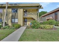 Inviting condo exterior with a well maintained lawn, colorful flowerbeds, and staircase leading to the second floor at 600 N Boundary Ave # 118B, Deland, FL 32720